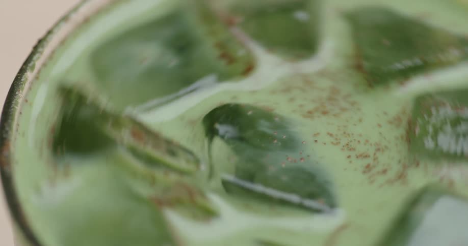 Stirring a green drink with ice cubes and cinnamon