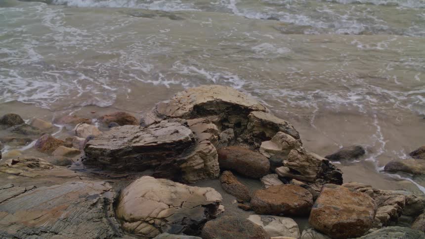Sea waves hitting rocks at midday