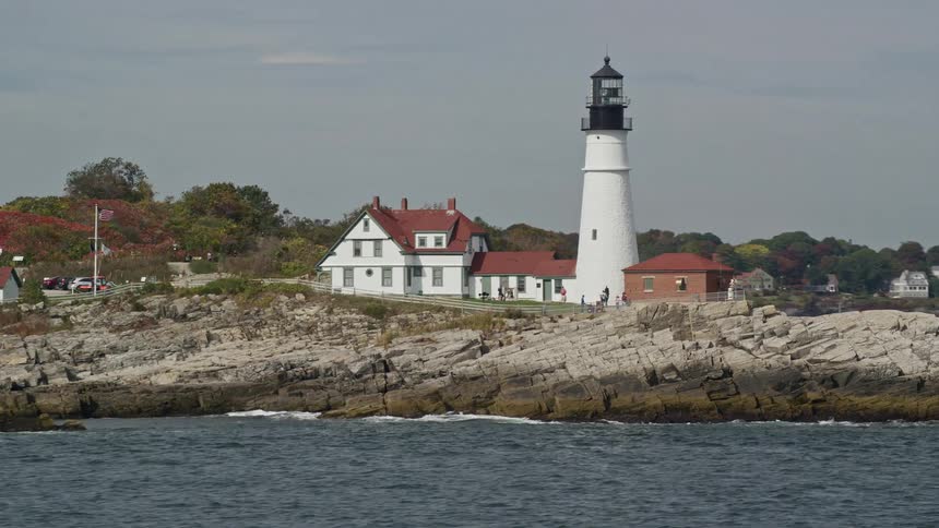 People playing near a lighthouse on a small hill at midday