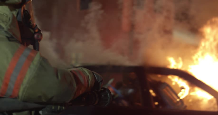 Firefighters carrying a house to a car fire at night