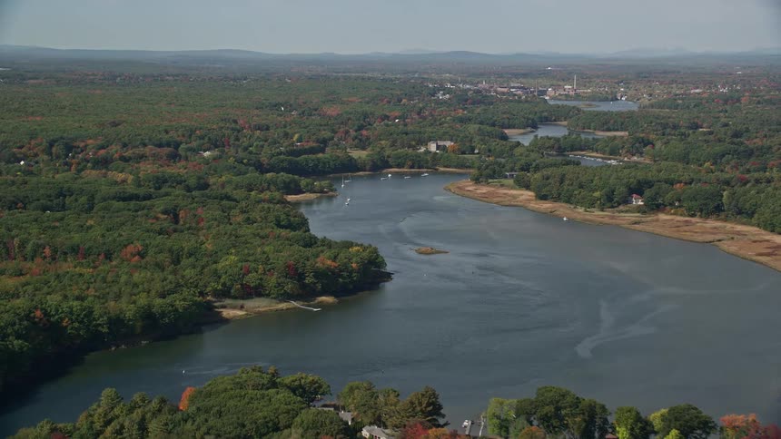 Aerial panorama of houses by the edge of a lake surrounded by a forest