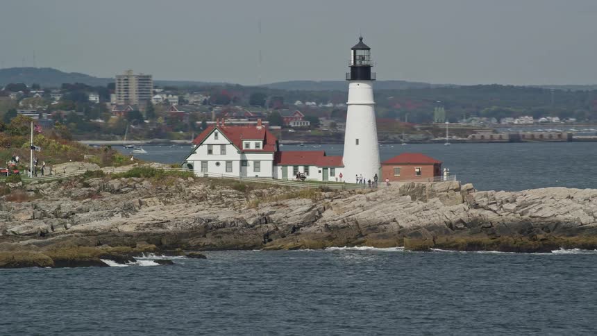 People are standing around the light house by the shore
