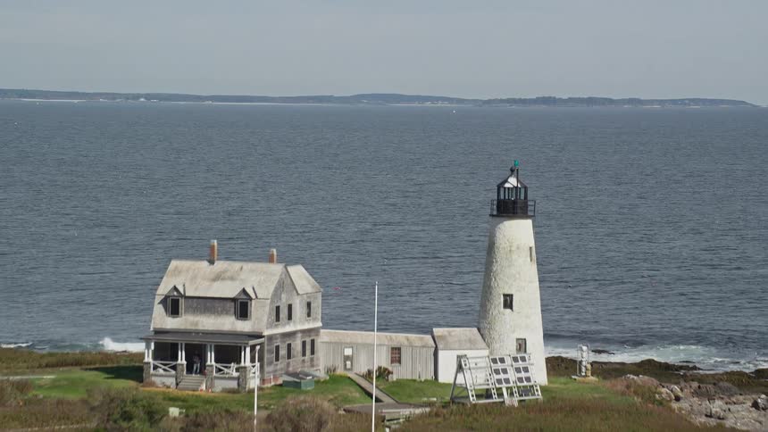 A white lighthouse on top of a small island surrounded by the sea