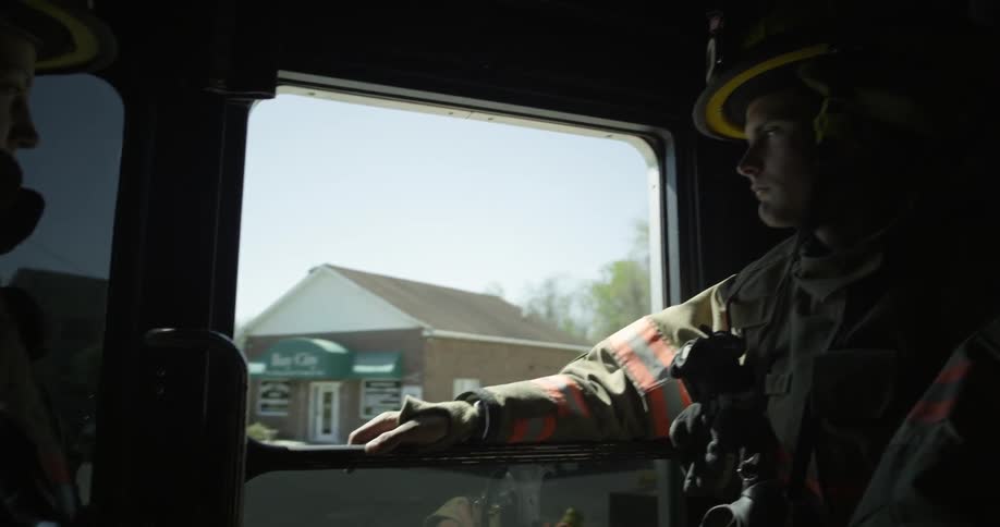 A fireman looks out the side of a moving truck window
