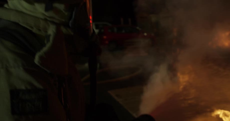 A firefighter uses a hose on a burning car