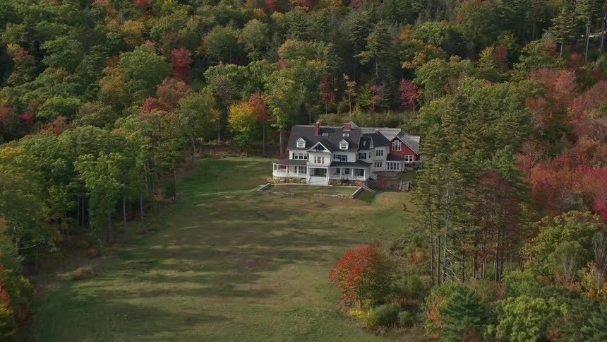 An estate home is surrounded by a forest of trees in bright fall colors