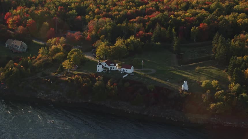 An aerial panorama of a waterfront residence on an island with a forest