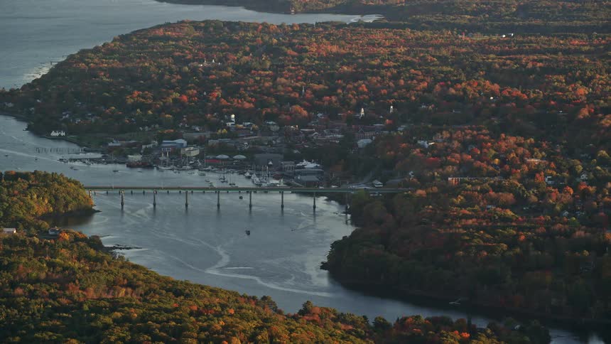 An aerial view of a bridge that passes over a river near a coastal town