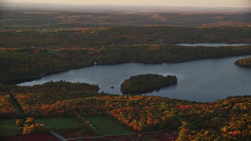 Aerial view of lake surrounded by trees with fall color