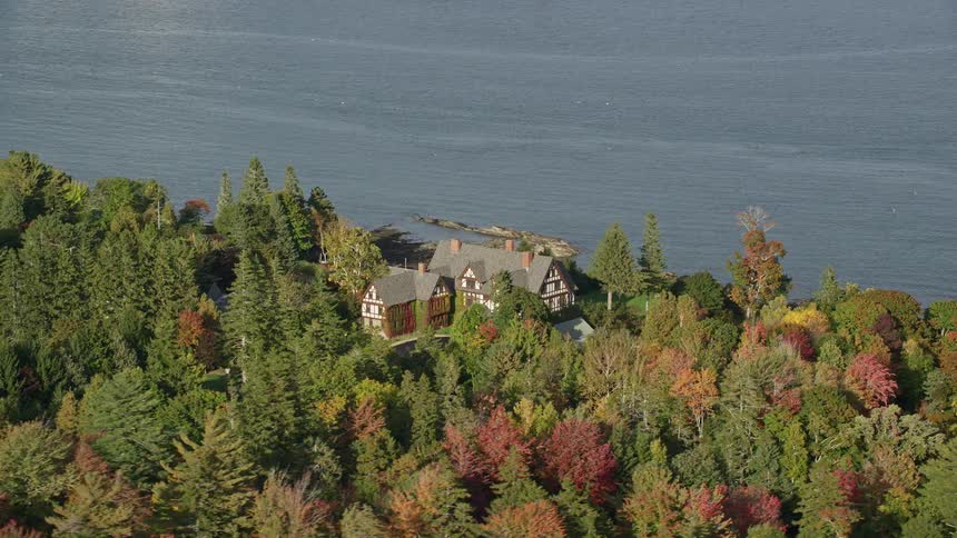 An aerial view of a rural manor in a forest by the coast