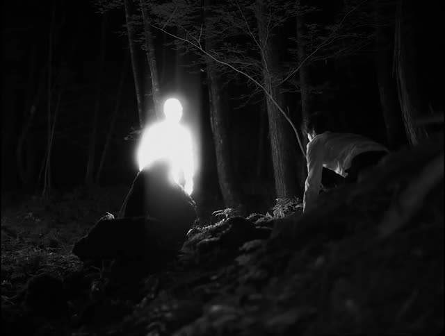 A man putting on white bowing for another man glowing in light