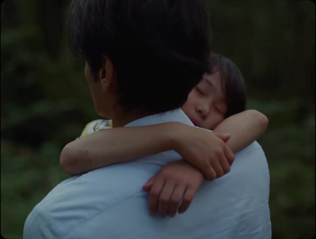Father walking with his son in his arms through the forest