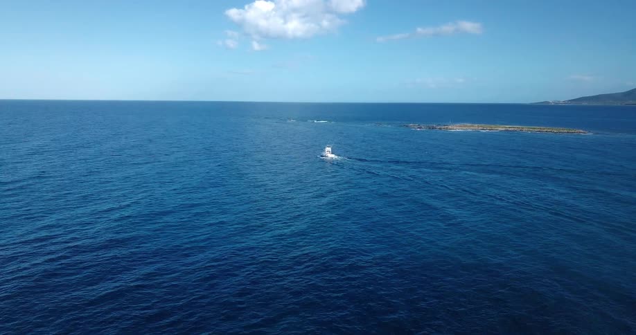 Aerial view of a motorboat next to an islet in the ocean