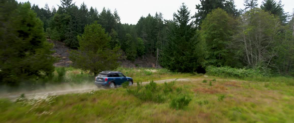Blue car driving on a dirt road in the countryside