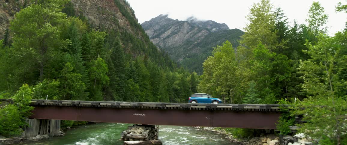 A car passing on the bridge over the river in the forest during a cloudy day