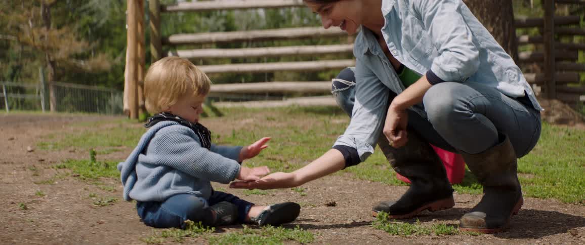 Mother plays with son outdoors in yard of rural property