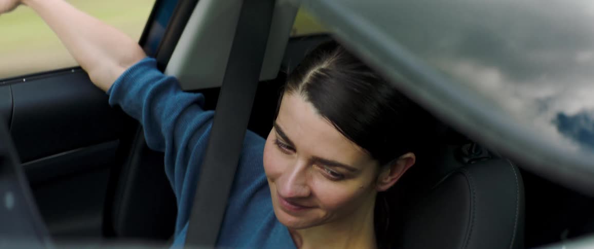 Dark haired woman rides in vehicle as seen through sun roof