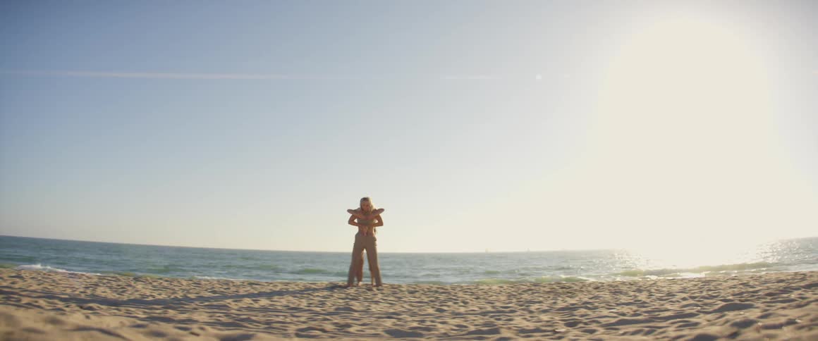 Two female dancers perform routine on beach on sunny day