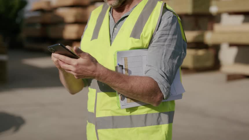 A construction worker is using his cell phone