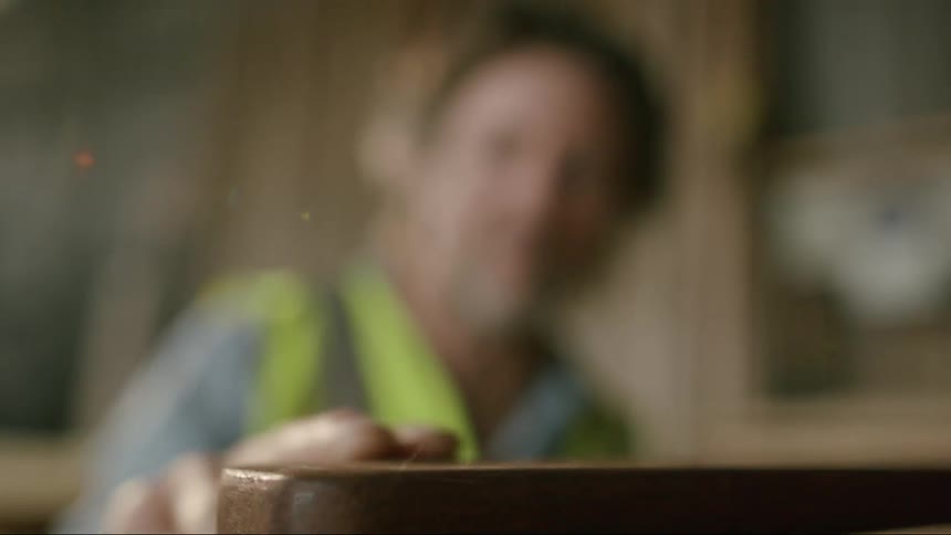 A man running his finger across dark wood
