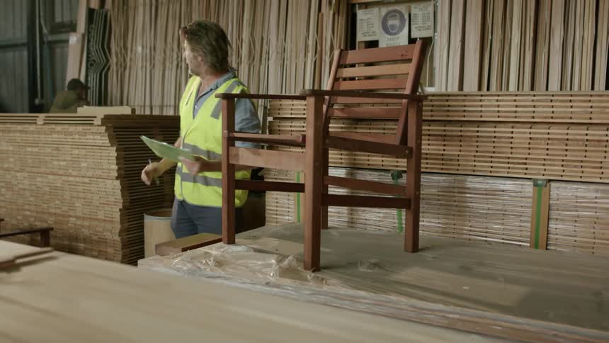 Man inspecting the production of a chair and conversing with a colleague