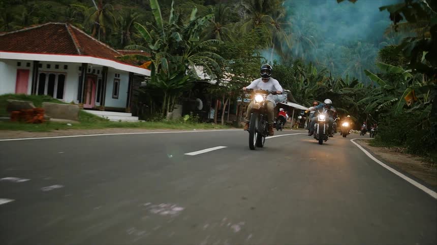 A group of people riding down a street on motorcycles