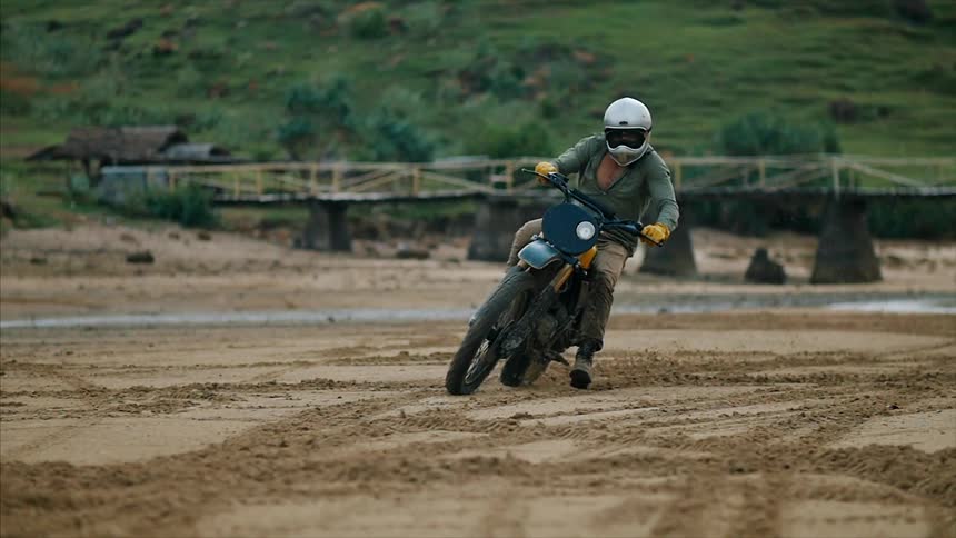 A man drives along a dirt field on a dirt bike