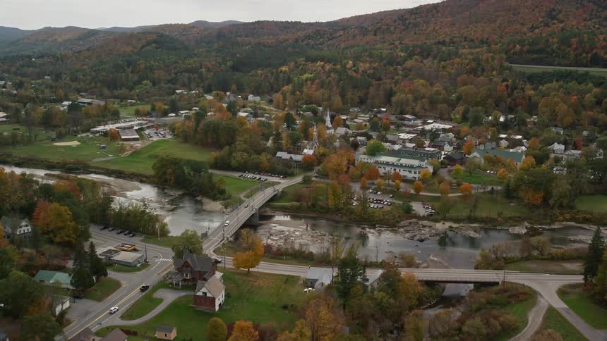 A rural region with some houses and a bridge that goes over a river