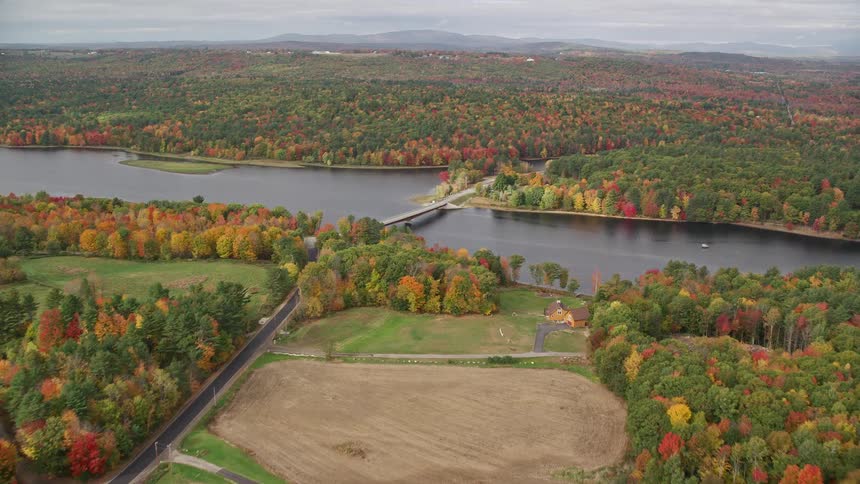 An aerial panorama of a natural area with houses by the edge of a lake