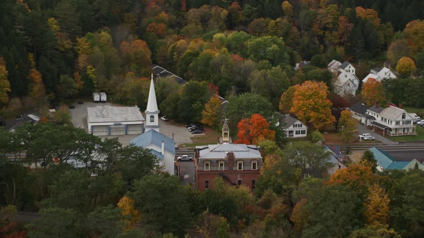 A suburban town with series of residential buildings including a church as they are mostly surrounded by a tree