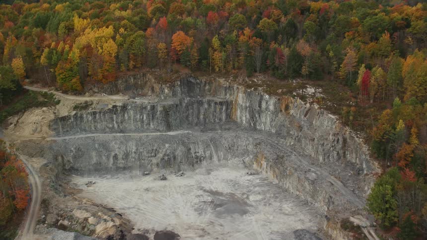 A quarry with rock excavated from a hill full of trees