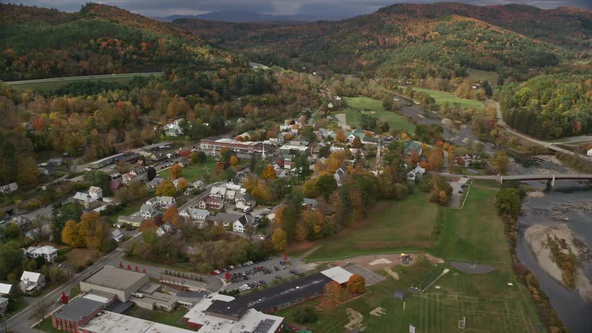 A small town with residences and a bridge that passes over a river that is almost dry
