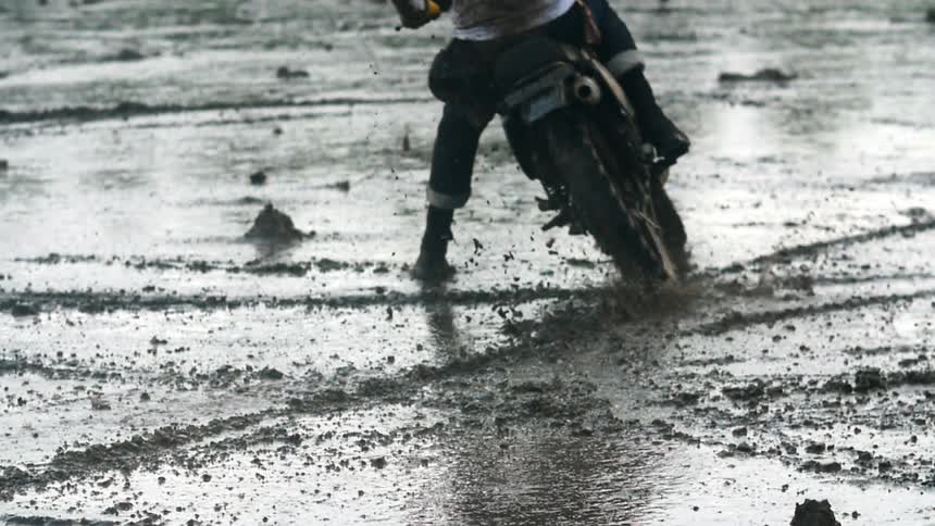 Motorcycle rides on a wet muddy beach