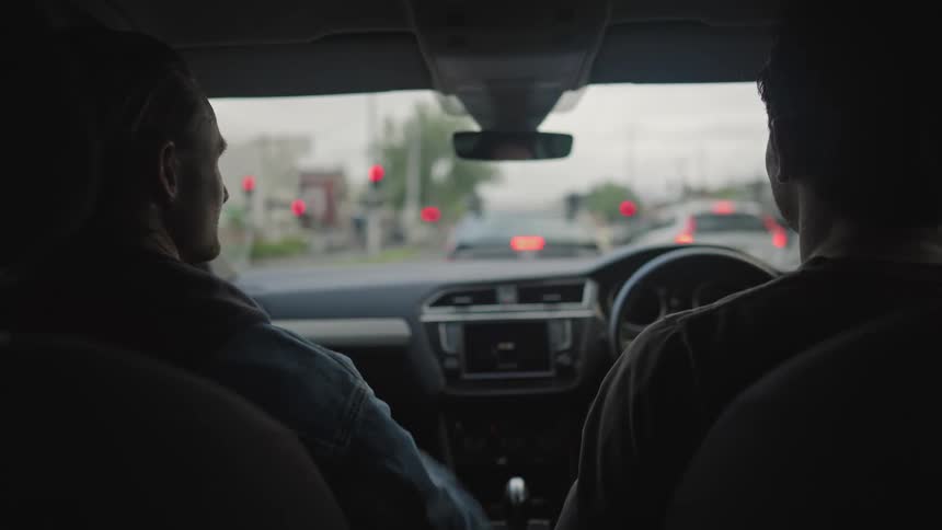 Two friends sitting in a car talk while waiting in traffic