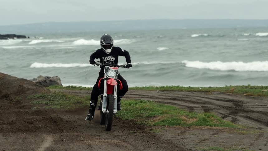 Motorcyclist taking off quickly in the dirt away from the beach