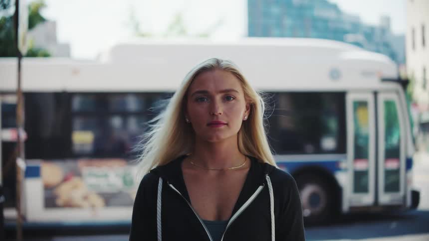 A bus passes behind a woman