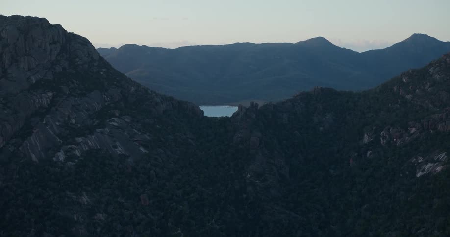 An aerial panorama of a mountain range with the sea in the background under a dawn sky