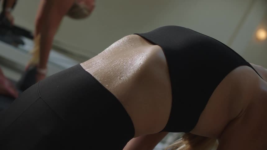 A young white lady wearing black sporting outfit is stretching as she lean backward