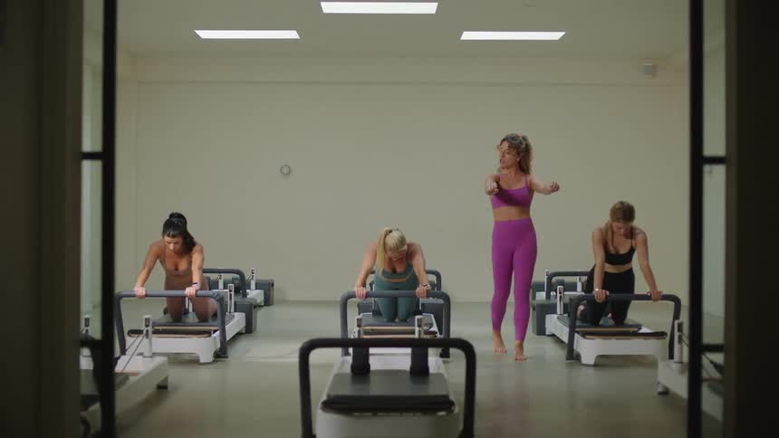 Four women in a room with three stretching on a machine and the fourth one happens to be their instructor