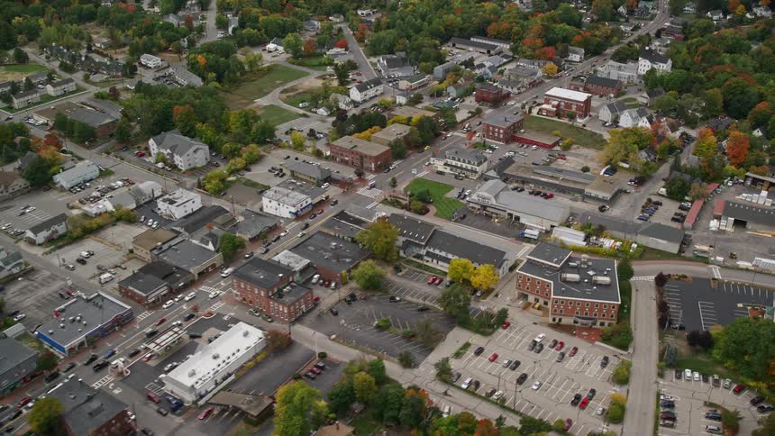 Traffic flows through town surrounded by trees with fall foliage