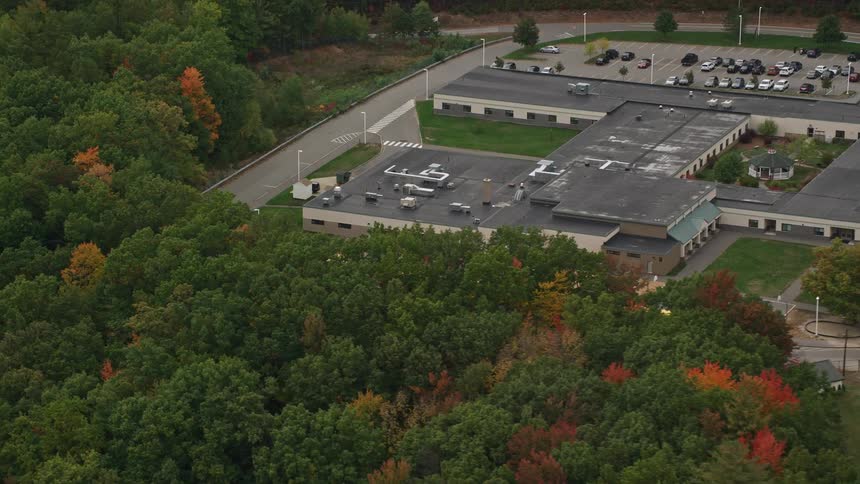 Aerial view of a school surrounded by green fields and trees
