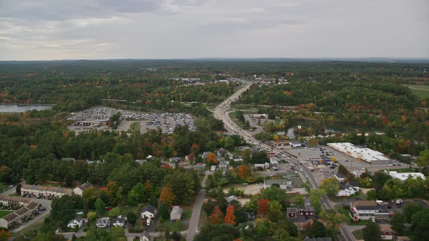 An aerial panorama of an urban city and a large parking lot with cars amidst areas with abundant vegetation