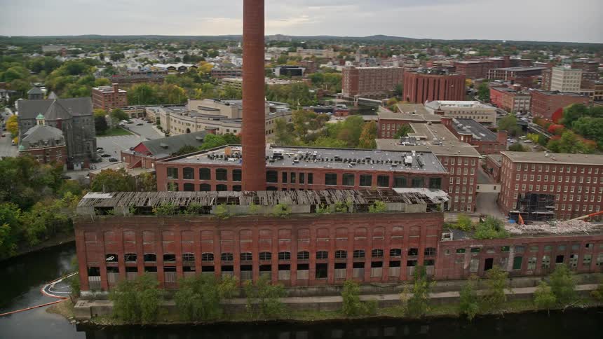 Aerial view flying by a riverside abandoned factory