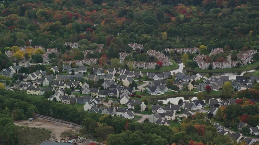 Aerial of a quiet neighborhood with small houses surrounded by forest