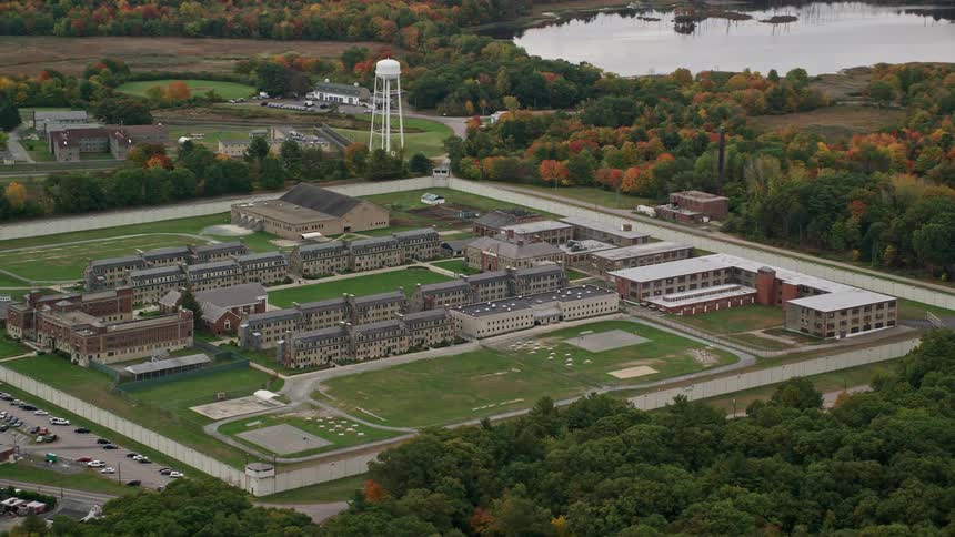 Aerial perspective of massachusetts correctional institution at norfolk encircled by trees displaying a mix of fall foliage during the autumn season