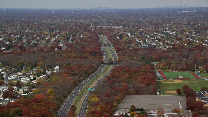 Many vehicles drive along a large freeway that passes through residential area