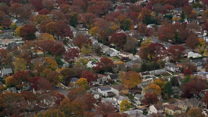 Suburbs of a city with several houses and many trees with leaves turning red