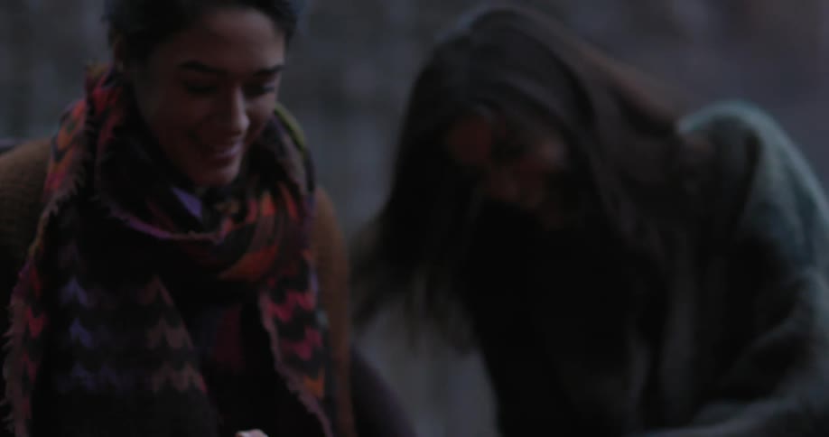 Women smiling and laughing while sitting in chairs outside at night
