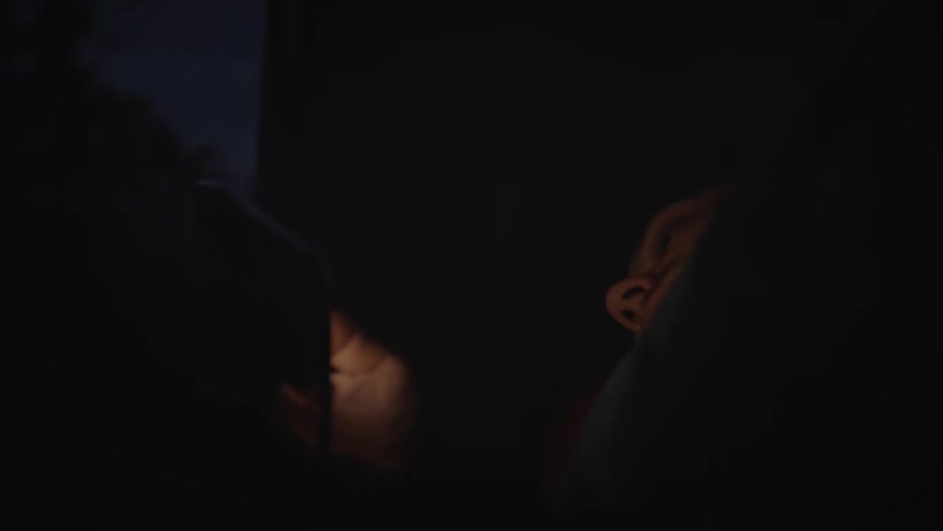 A person lying on a bed and using a device with a bright screen