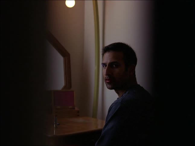 A clip of an adult man sited in front of the mirror and looking at the door